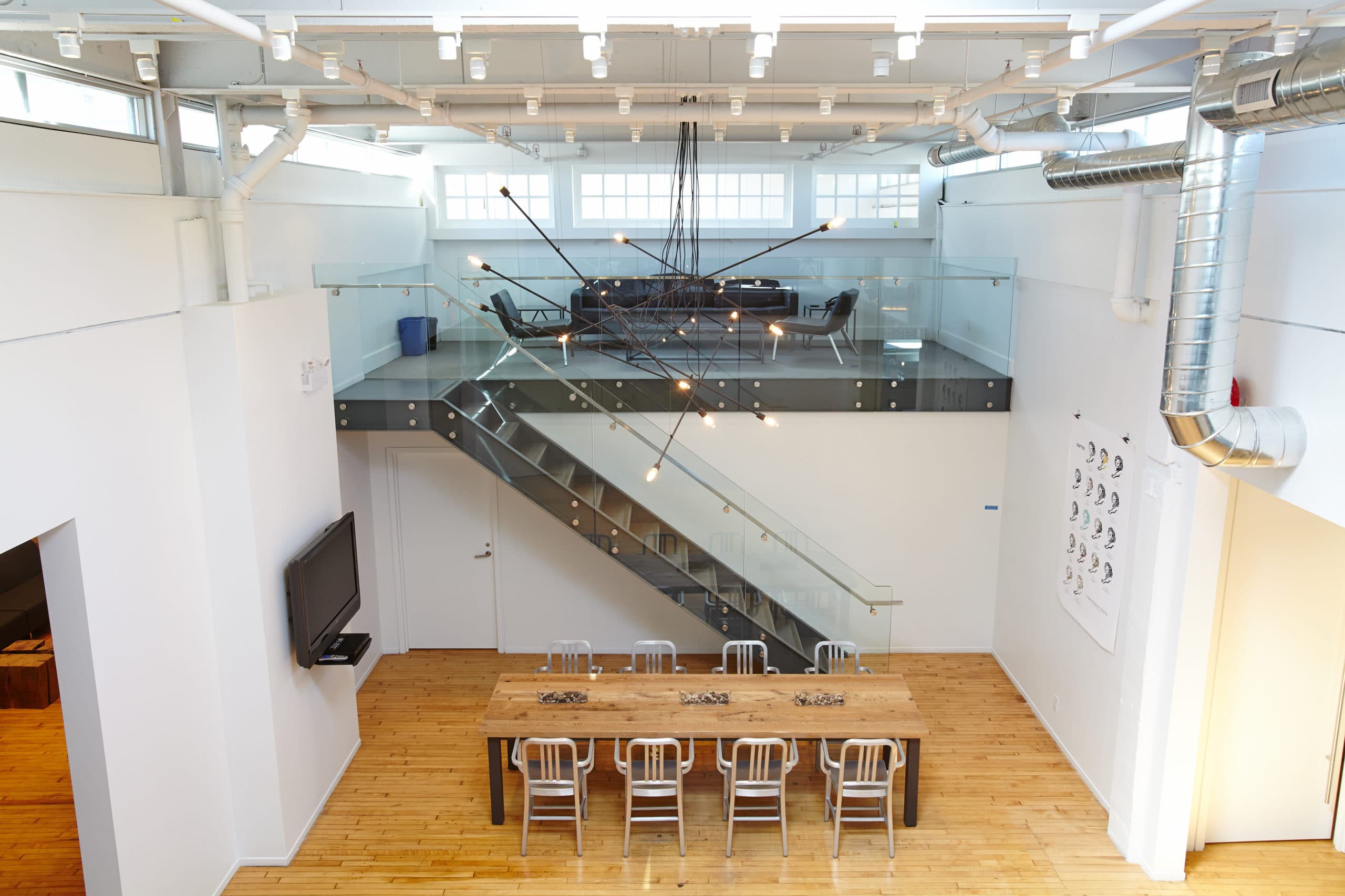 A soaring double height creative space with an open steel stair and exposed structure