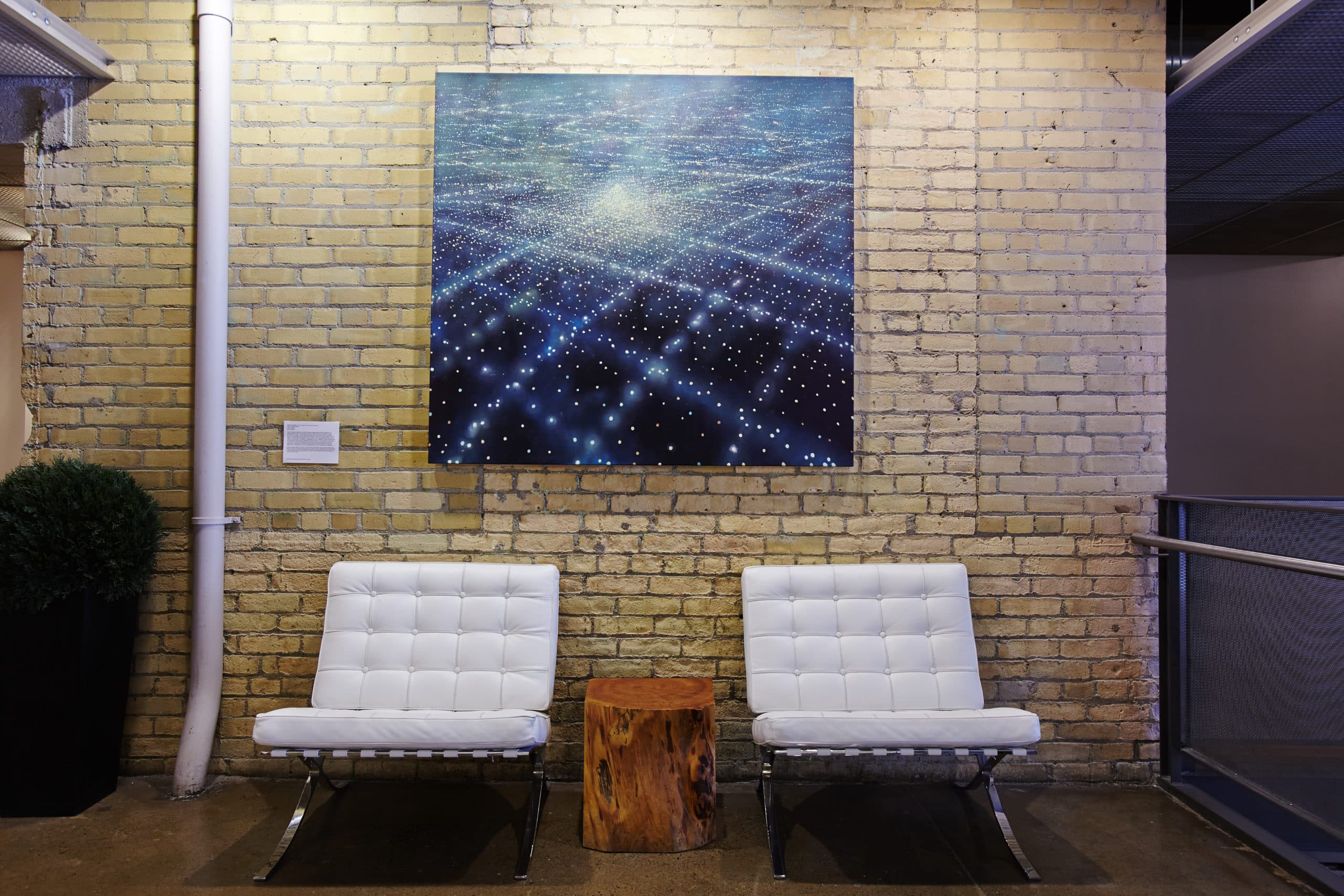 A luminous artwork mounted on the building's original brick wall in a common area lounge