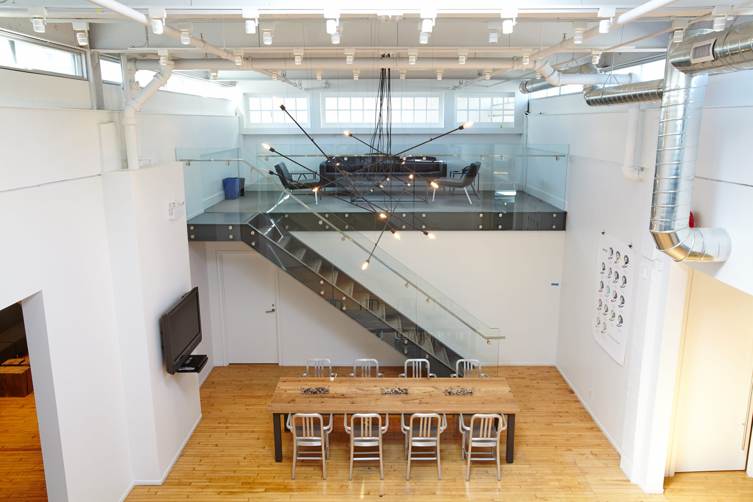 A soaring double height creative space with an open steel stair and exposed structure
