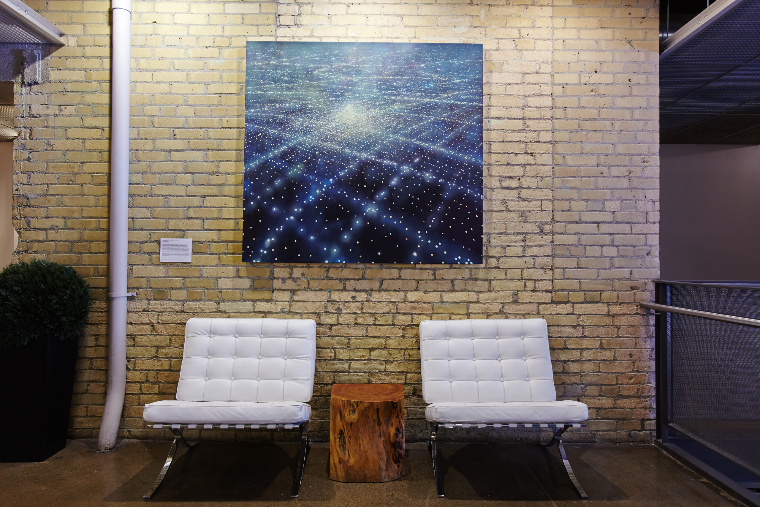 A luminous artwork mounted on the building's original brick wall in a common area lounge