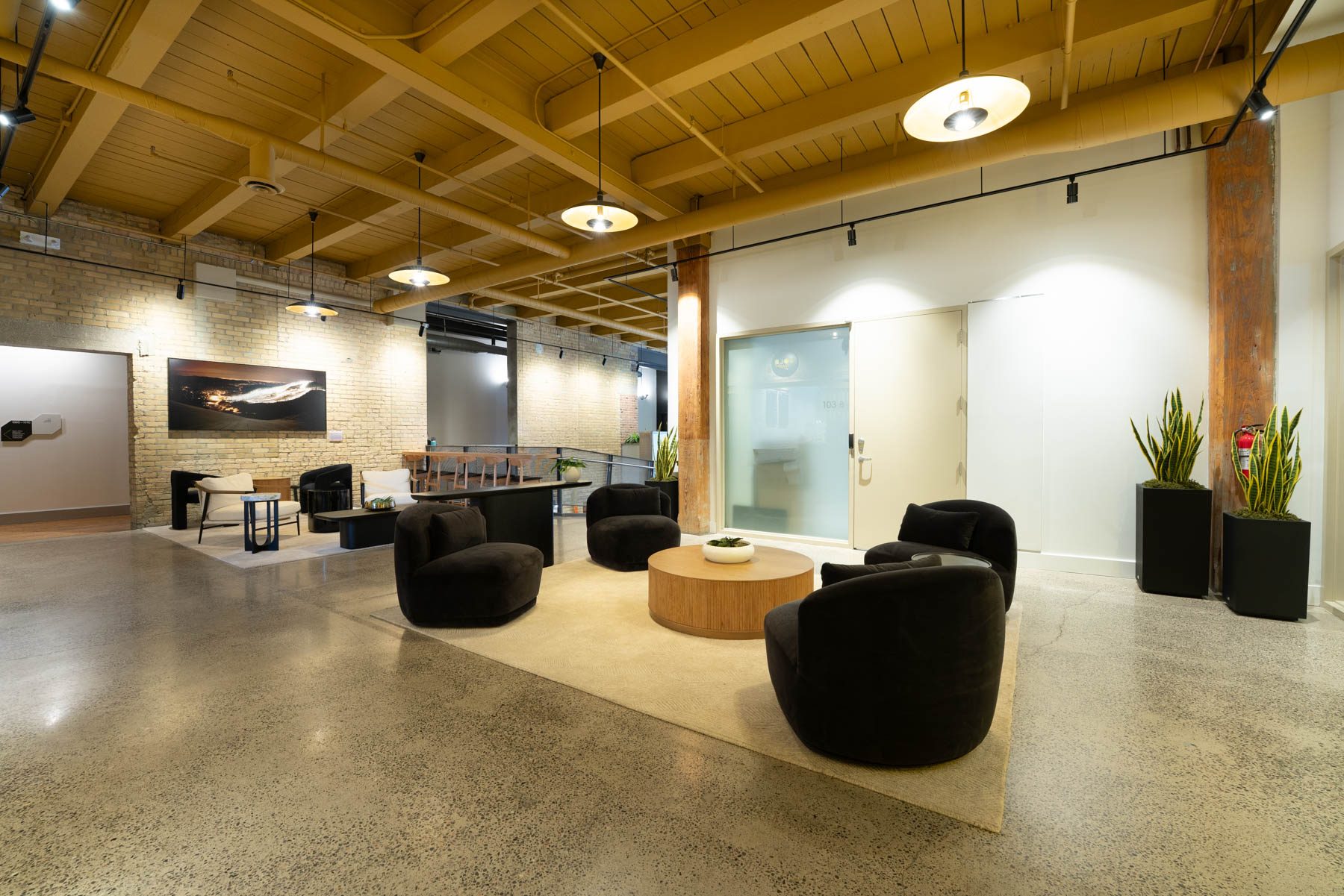 A renovated lobby at Light Factory with lounge chairs, a round table and exposed timber beams