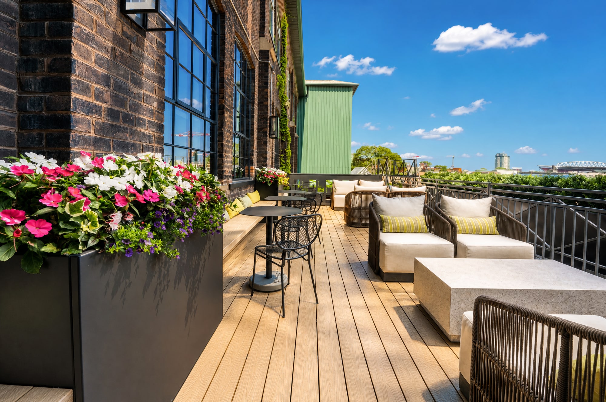 A rooftop patio deck with lounge seating and flower boxes under a blue sky over Liberty Village
