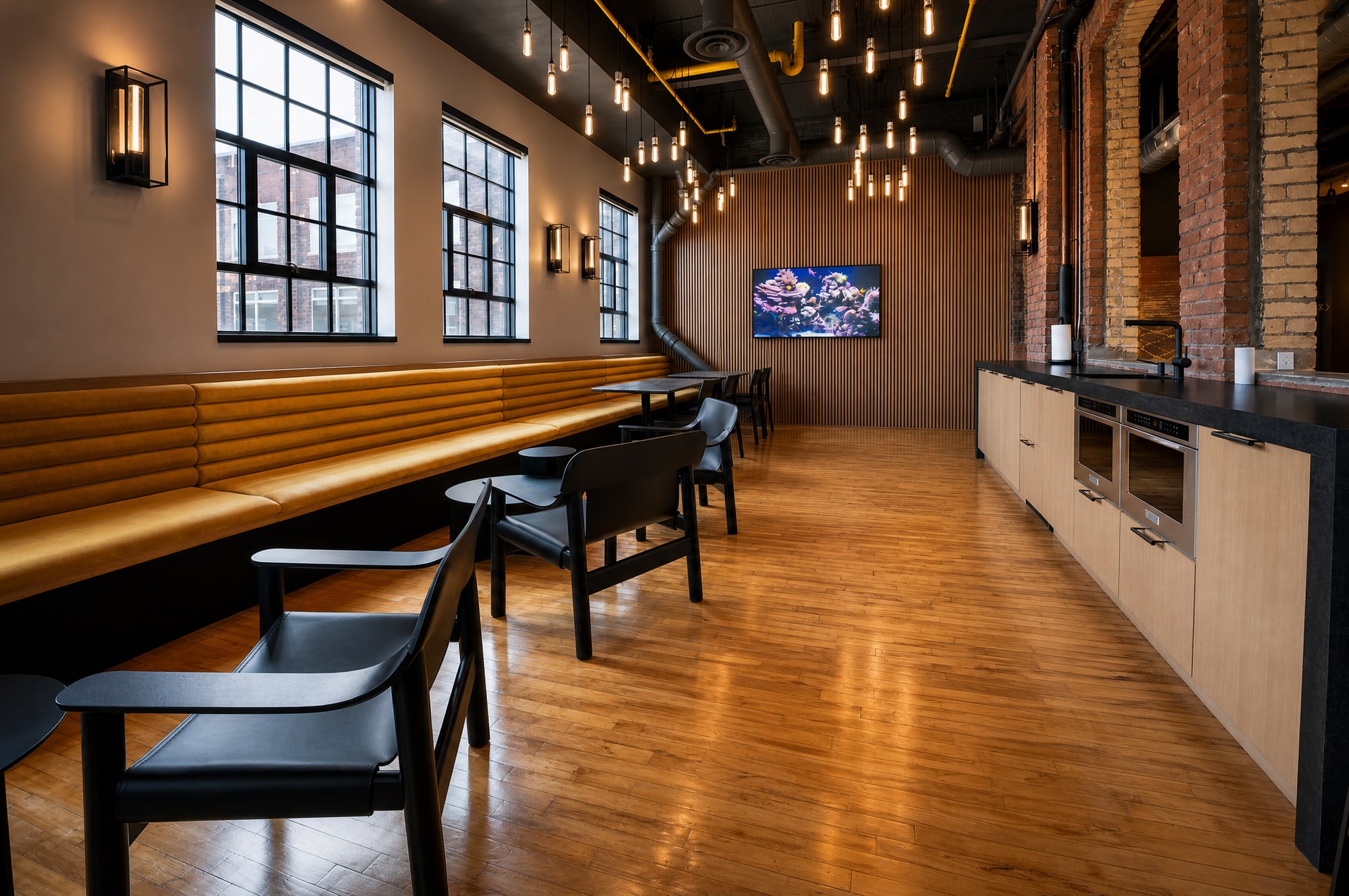 The indoor tenant lounge with a leather banquette, wood slat feature wall and industrial pendant lighting